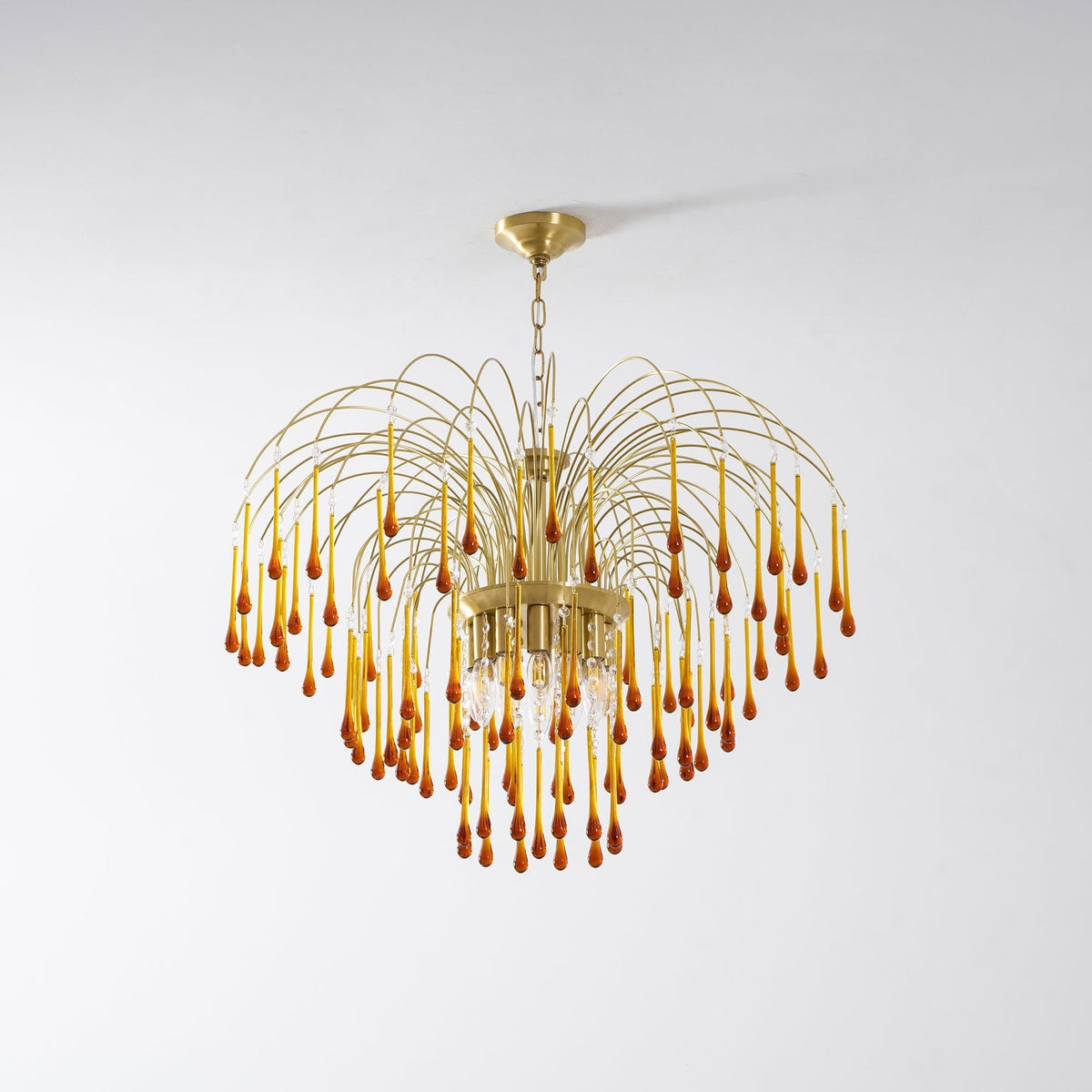 The fullest tiers of caramel crystal drops on this Clérachic pendant are shown lit on a plain light background.