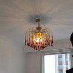 Sunburst light rays spread across the ceiling around this Clérachic chandelier, its caramel crystal drops lit warm near a city-view window.