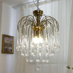 Clear crystal drops on this Clérachic chandelier hang beside a small framed picture, lit with a soft warm glow.