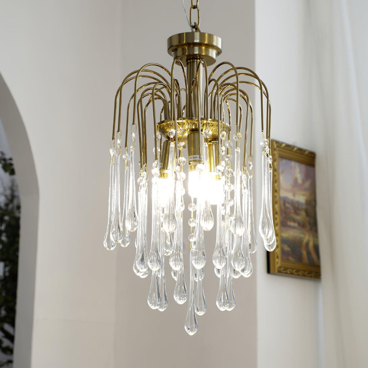 This Clérachic pendant hangs near an arched doorway and framed picture, its clear crystal drops lit warm.