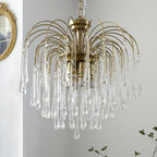 This Clérachic chandelier's clear crystal drops fan out beside a small potted plant on a plain background.
