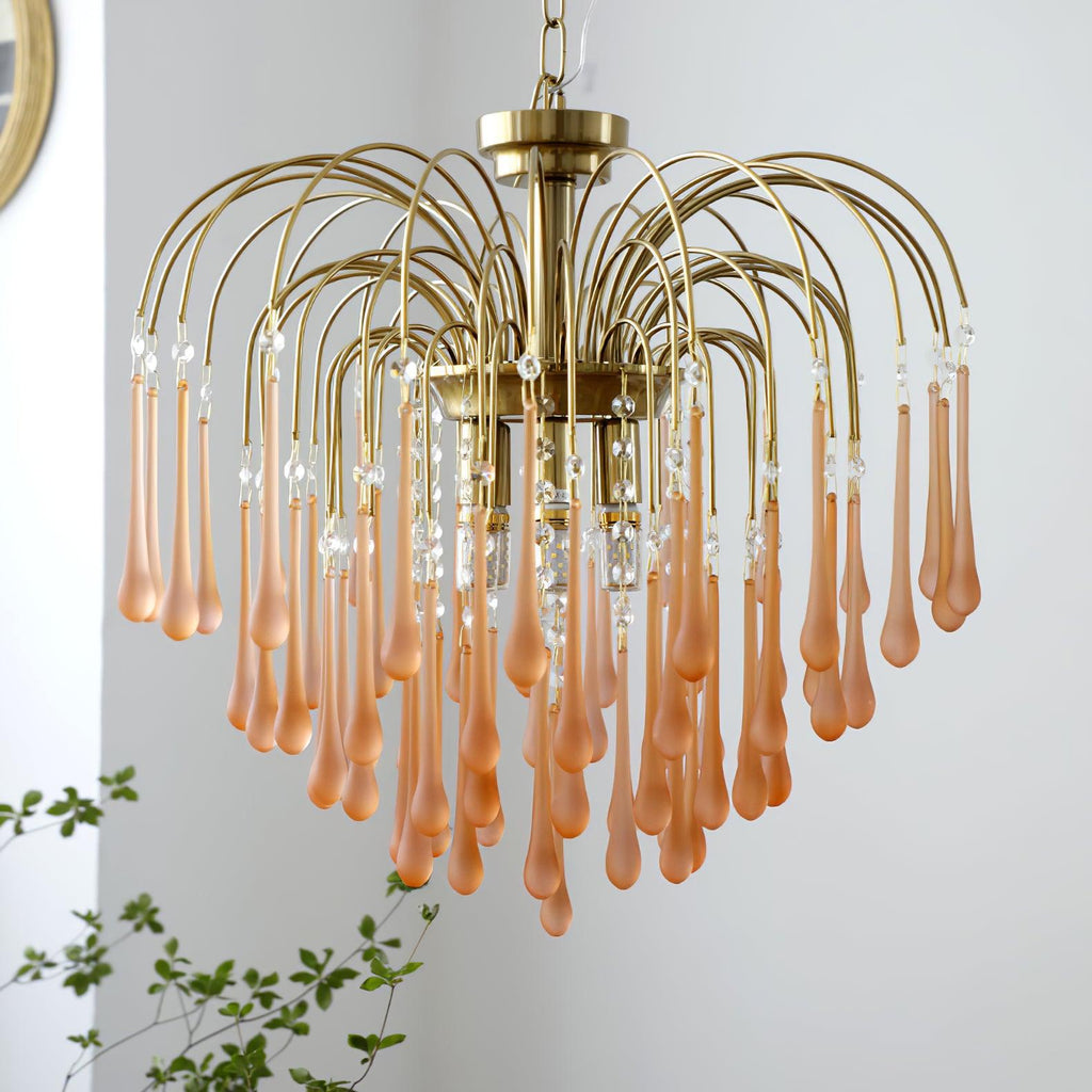 This Clérachic chandelier's blush-caramel crystal drops cascade in wide tiers beside a small potted plant.
