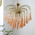 This Clérachic chandelier's blush-caramel crystal drops cascade in wide tiers beside a small potted plant.