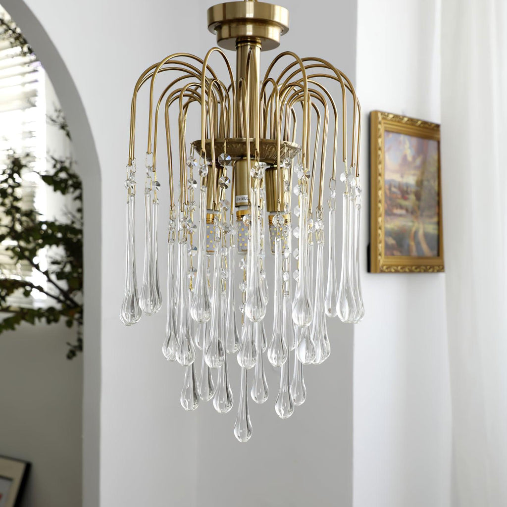 Clear crystal drops on this Clérachic pendant hang near a framed picture beside an arched white doorway.