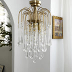 Clear crystal drops on this Clérachic pendant hang near a framed picture beside an arched white doorway.
