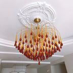 This Clérachic chandelier hangs beneath an ornate ceiling medallion in a hallway with a round mirror on the wall.