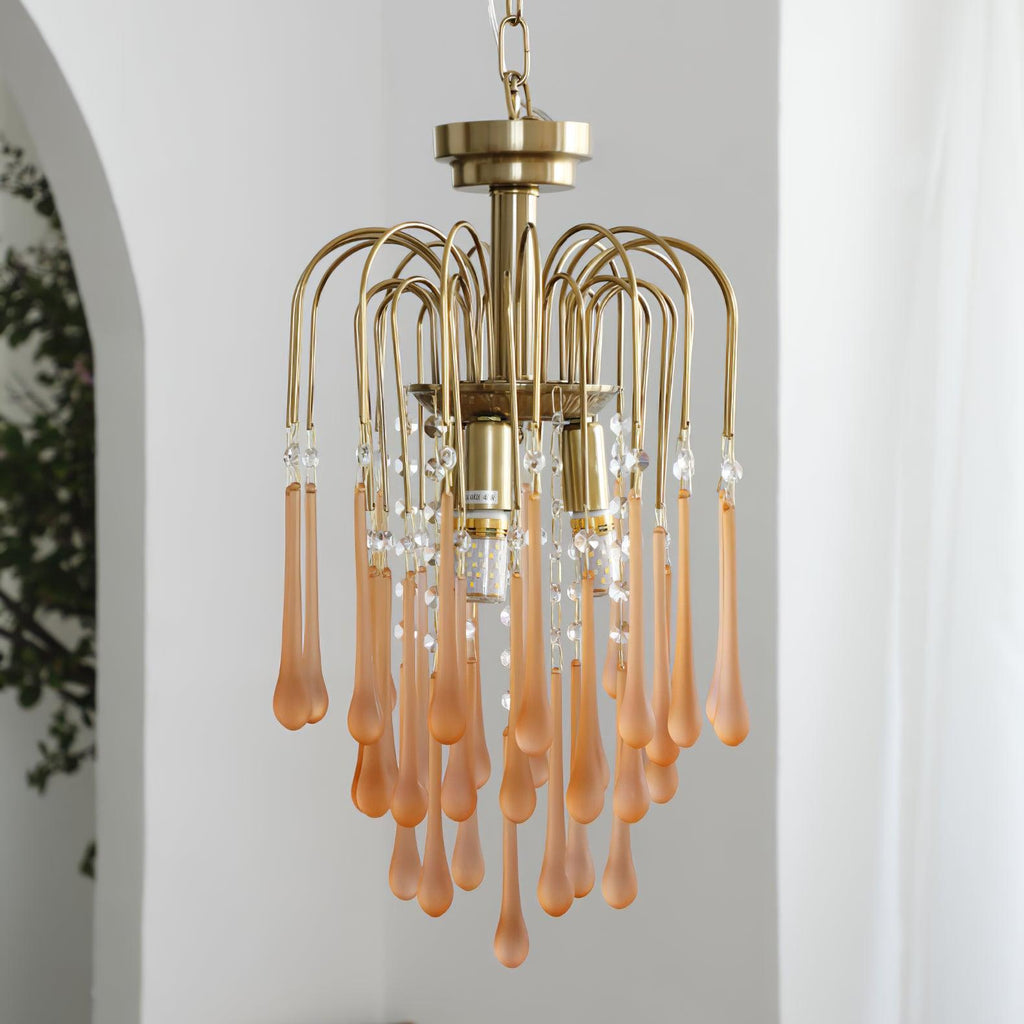 Blush-caramel crystal drops on this Clérachic pendant hang beside a leafy plant on a plain white background.