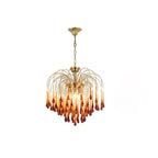 Caramel crystal drops on this Clérachic pendant are lit softly on a plain background, brass arms arcing overhead.