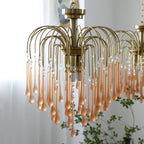 The same blush-caramel crystal drops on this Clérachic chandelier are shown closer, beside a sheer curtain and green plant.