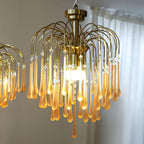 Looking up into this Clérachic chandelier, its lit bulbs sit among caramel and clear crystal drops beside a sheer curtain.