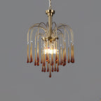 This Clérachic pendant's caramel crystal drops are lit against a plain dark grey background, brass arms fanning outward.