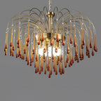 This wide-tiered Clérachic chandelier's caramel crystal drops are lit from within against a dark grey background.