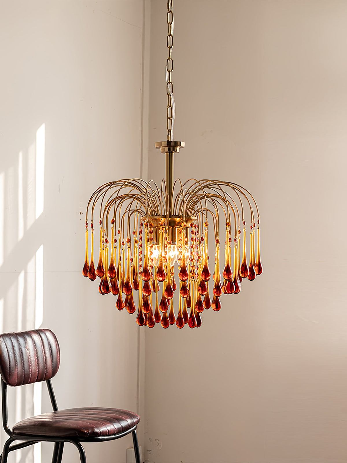 Morning light falls across the caramel crystal drops of this Clérachic chandelier, hung near a dark leather chair.