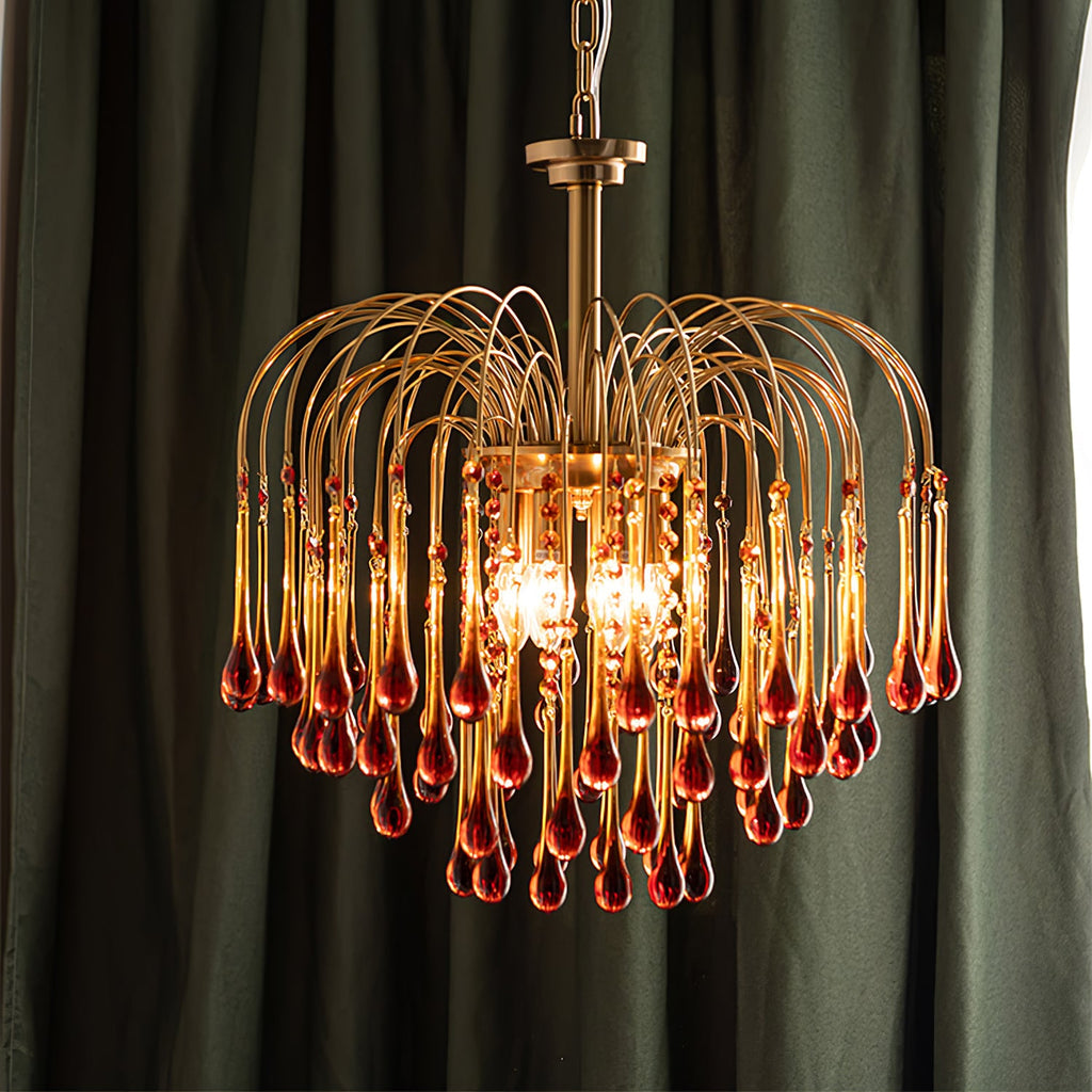 Caramel crystal drops on this Clérachic chandelier stand out against a dark green curtain, lit with a warm glow.
