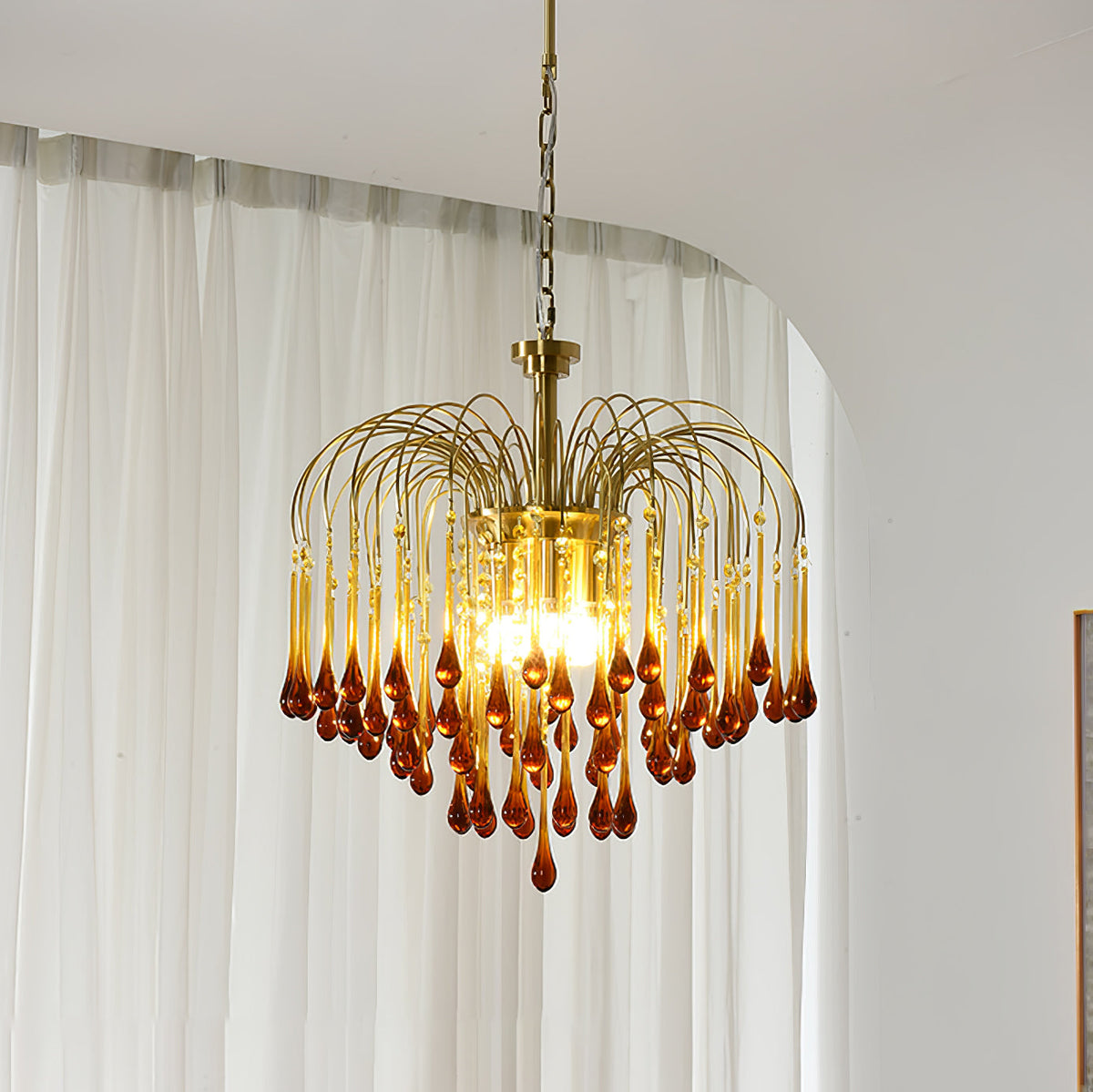 Sheer white curtains frame this Clérachic chandelier, its caramel crystal drops lit against the soft daylight.