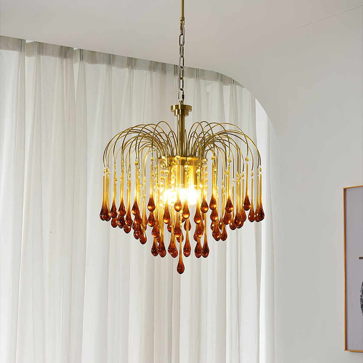 Caramel crystal drops cascade from this Clérachic pendant, hung beside a sheer curtain and the edge of a framed picture.