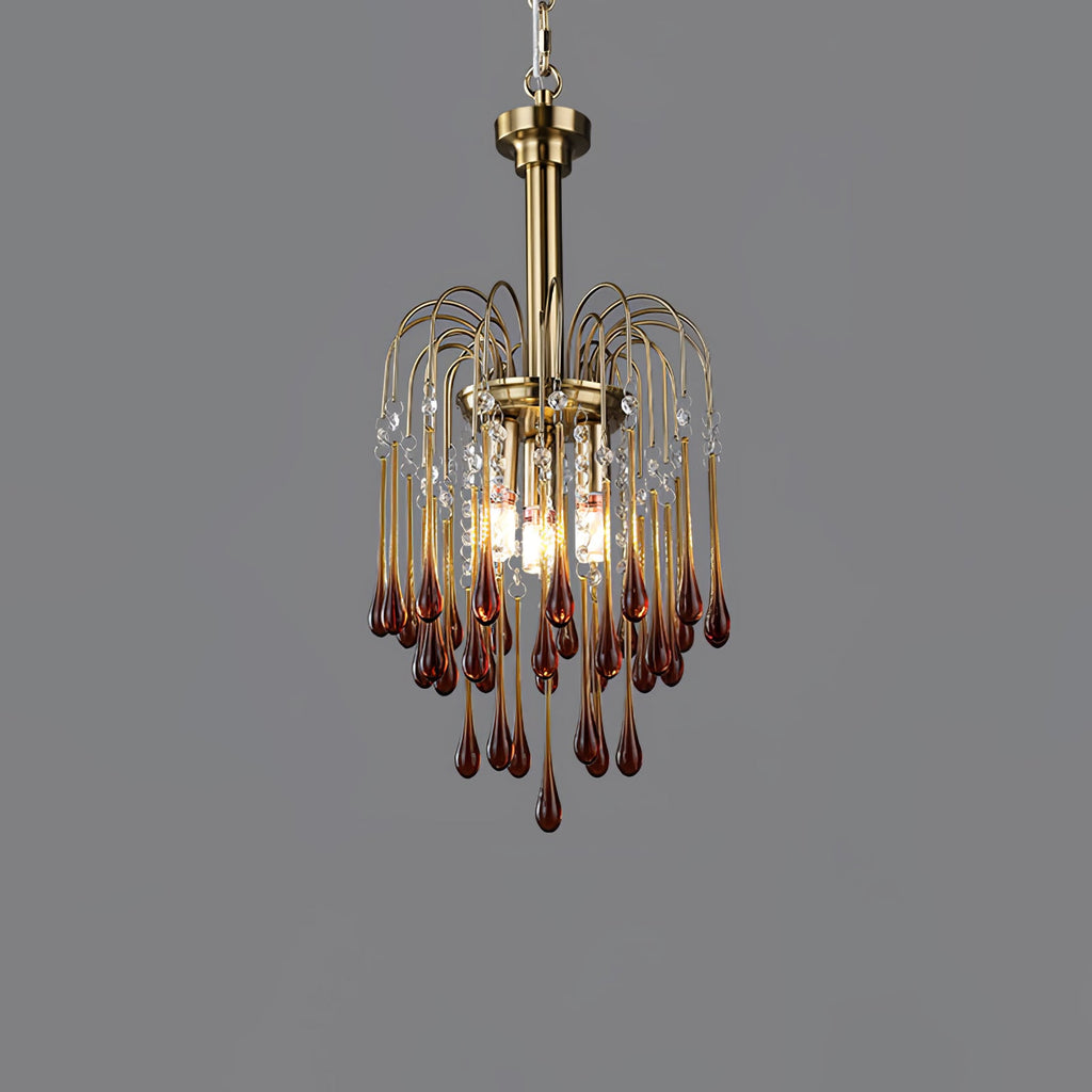 This Clérachic pendant's caramel crystal drops are lit against a dark grey backdrop, brass arms arcing above.