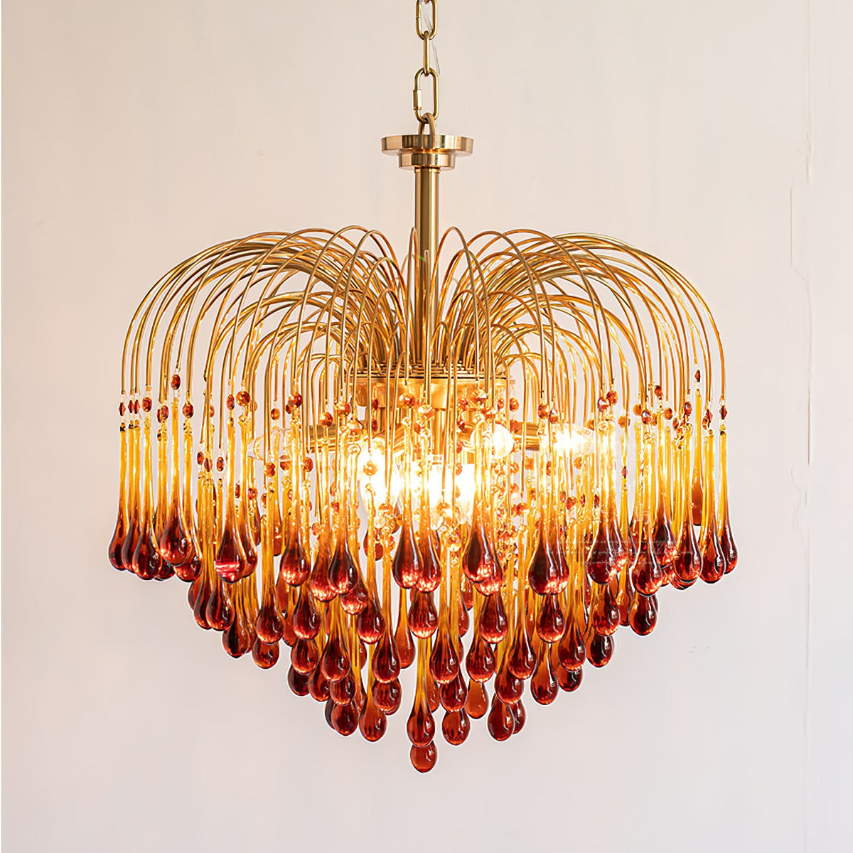 A larger tiered version of this Clérachic chandelier, its caramel crystal drops darkening toward the tips, shown lit on a plain background.
