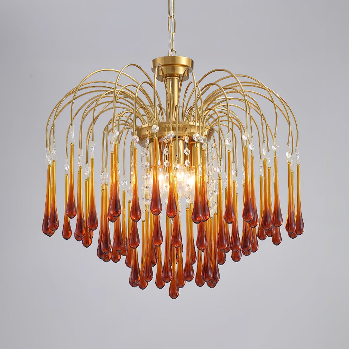 This large Clérachic chandelier's caramel crystal drops hang with clear accents, lit brightly on a plain background.