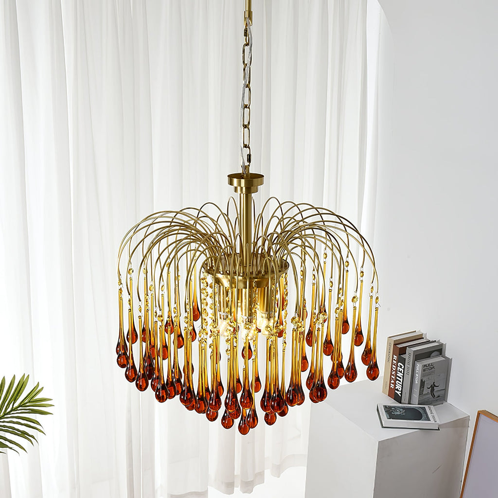 This Clérachic pendant's caramel crystal drops hang near a sheer curtain, with a small plant leaf and stacked books below.