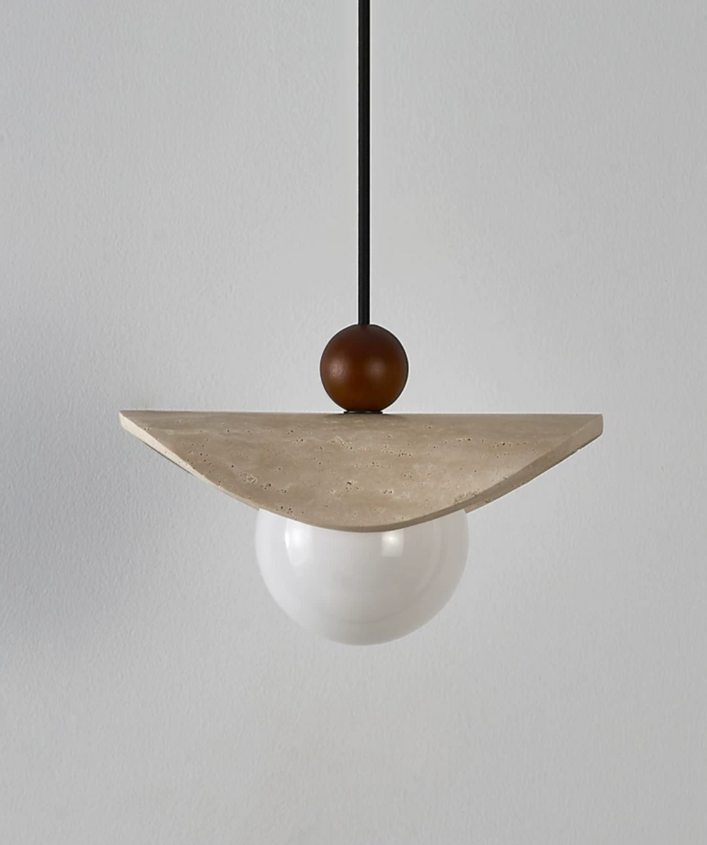 A travertine sail Clérachic pendant hangs from a black cord, shown against a plain grey backdrop.