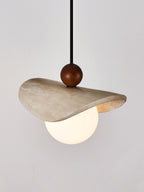Close product shot of this Clérachic pendant shows its travertine sail catching the light above the globe.