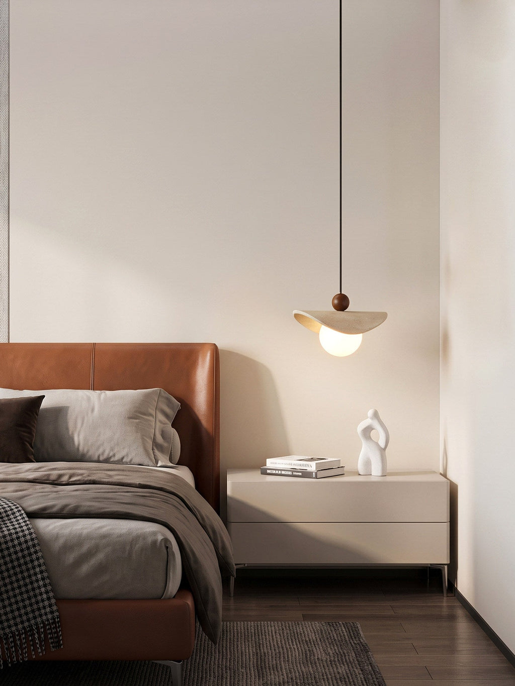 Close beside a tan leather bed, this travertine sail Clérachic pendant glows above a beige nightstand.