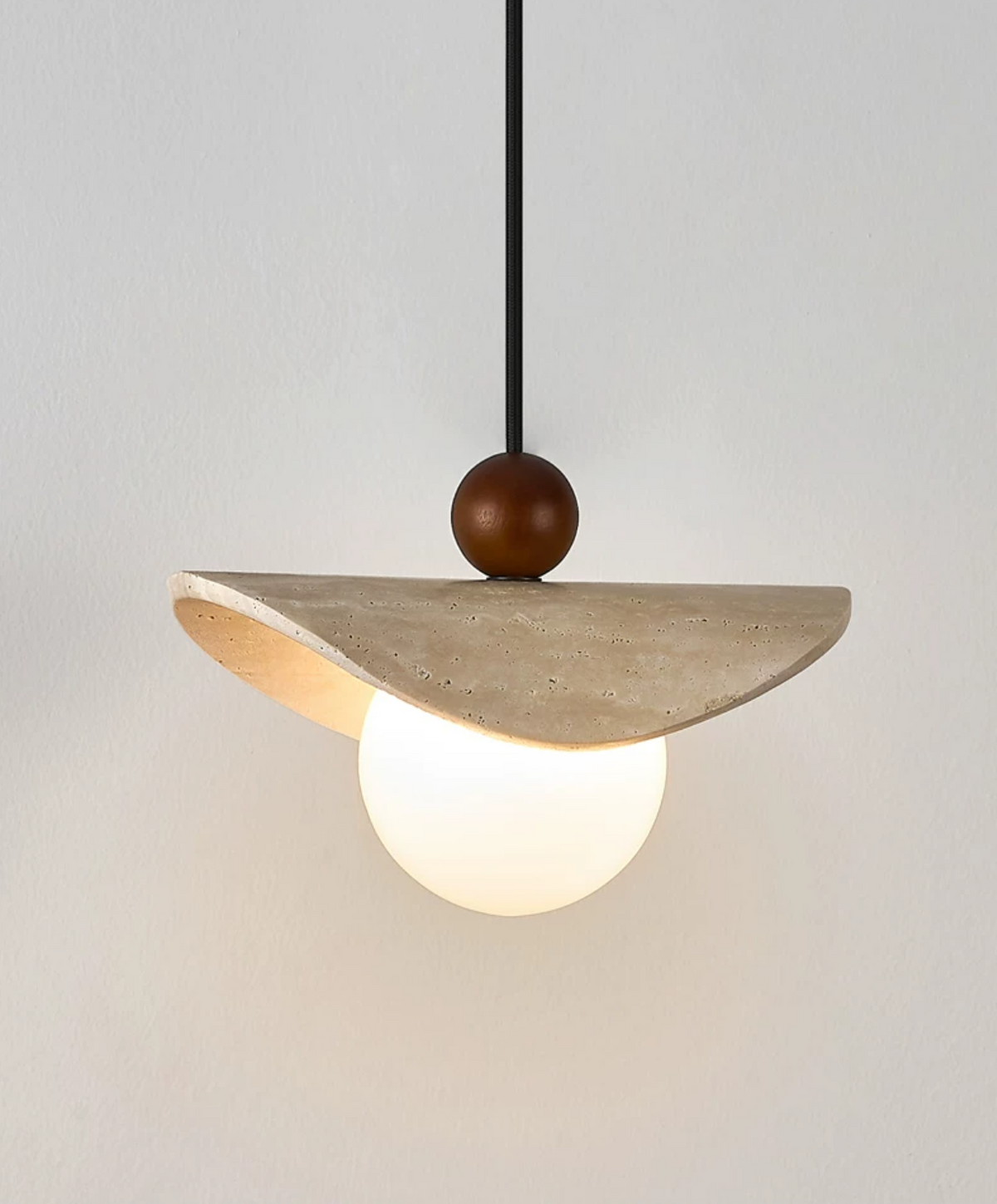 Close product shot of this Clérachic pendant's travertine sail, walnut bead, and glowing opal globe.