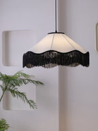 Tucked into a wall niche beside a small potted plant, this Clérachic pendant's fringe glows warm.