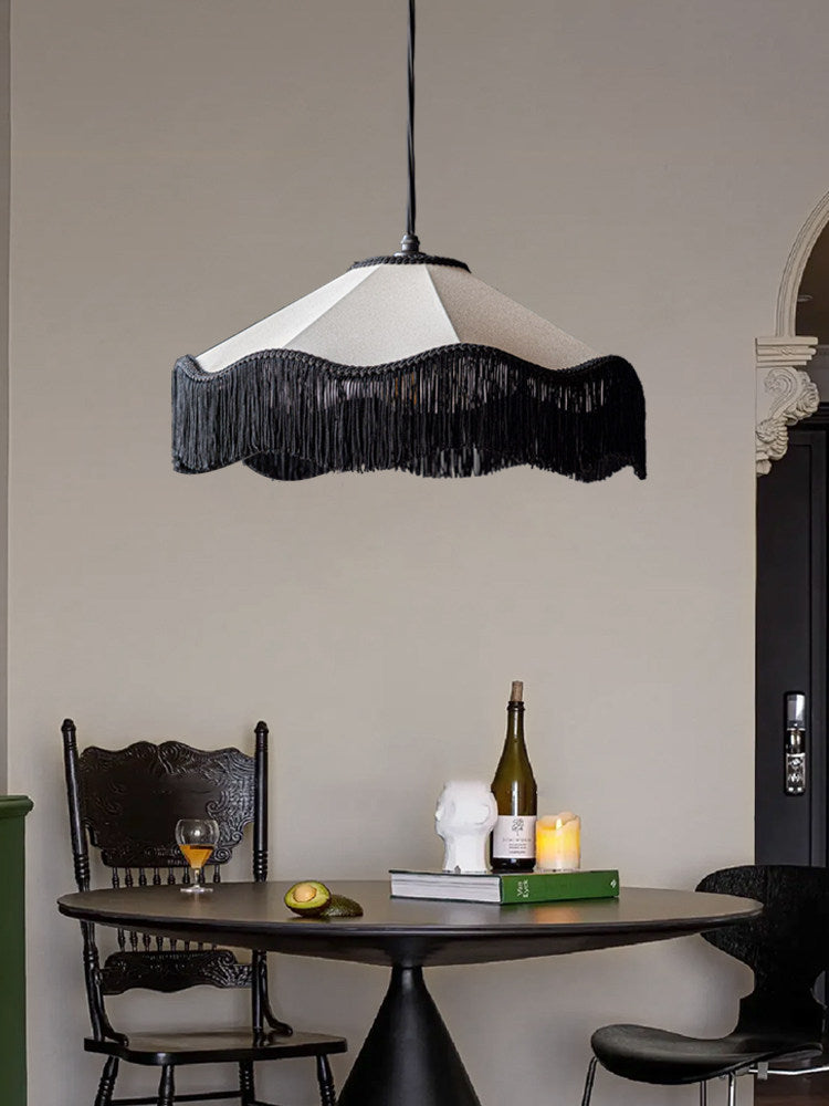 This Clérachic pendant glows above a round dining table set with a bust sculpture, wine bottle and candle.