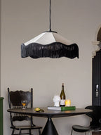 This Clérachic pendant glows above a round dining table set with a bust sculpture, wine bottle and candle.