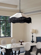 This Clérachic pendant glows warm above a white marble dining table surrounded by round-back chairs.