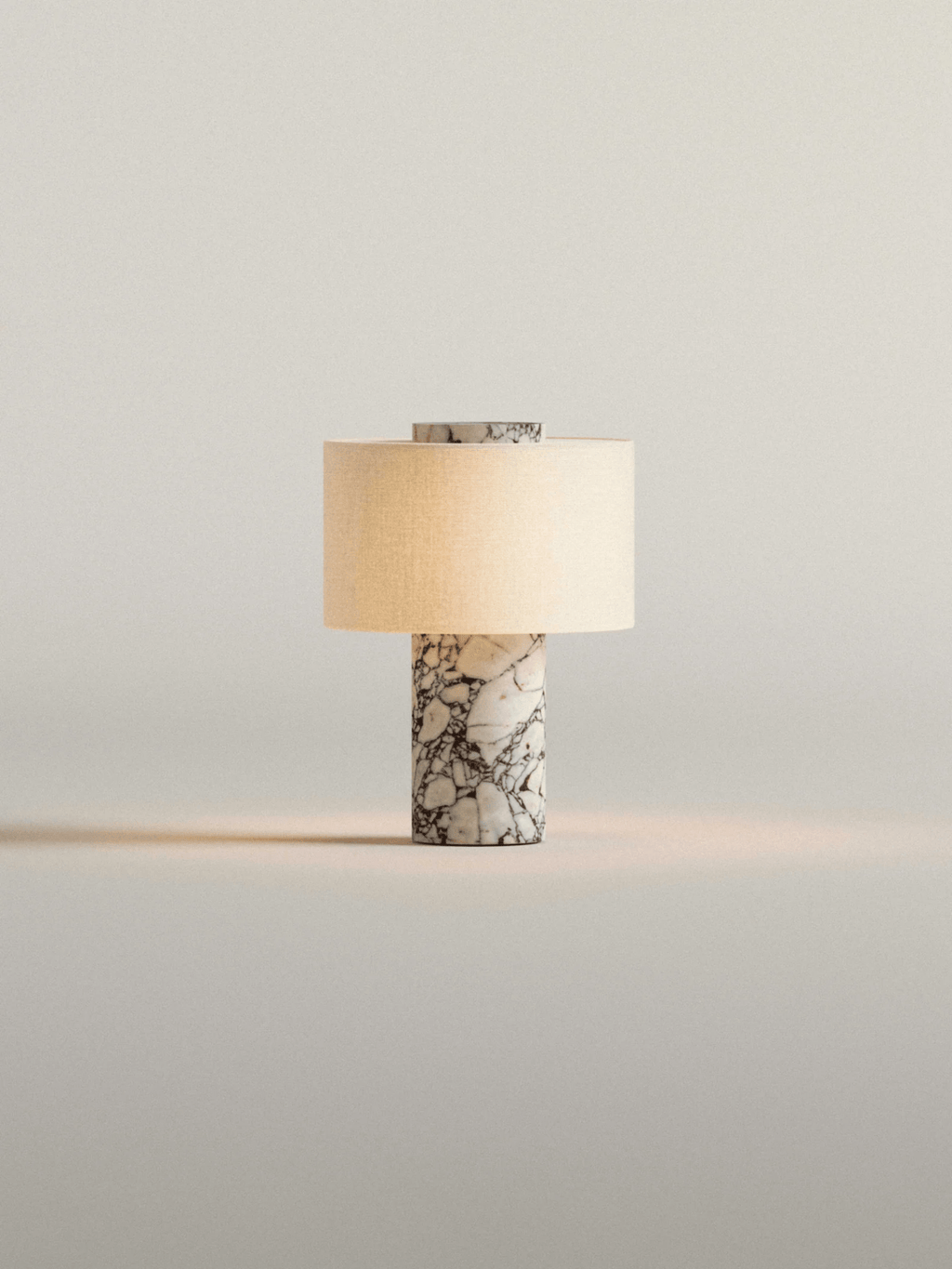 Another isolated shot of the Clérachic cordless table lamp, its white marble base lit warm on a plain background.