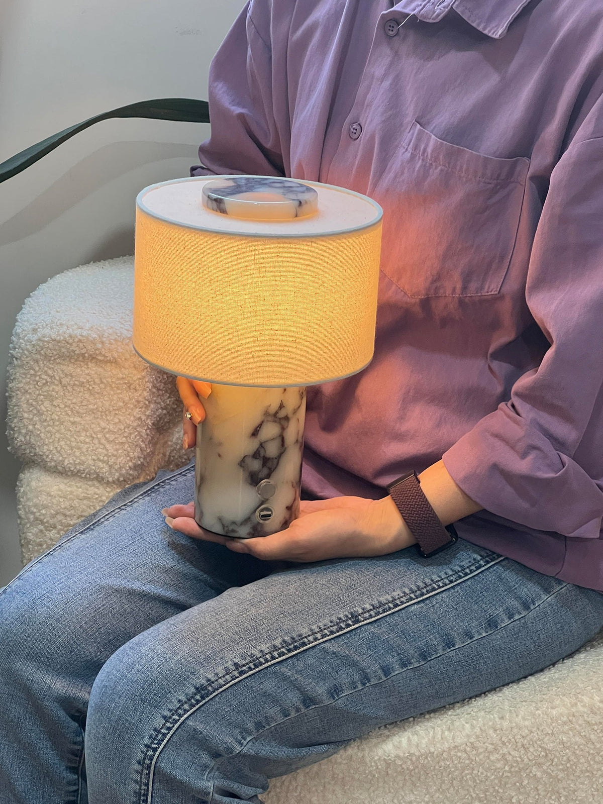 Someone holds the Clérachic cordless table lamp in their lap while seated, showing how light and portable this design is.