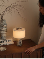 The Clérachic table lamp sits on a wooden sideboard beside a marble vase of dry branches and a stack of books.