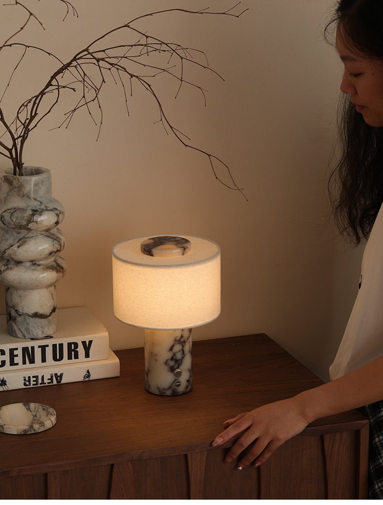The Clérachic table lamp sits on a wooden sideboard beside a marble vase of dry branches and a stack of books.