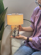 A woman lifts the Clérachic cordless table lamp in one hand, showing its light, portable rechargeable design.