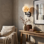 Next to a console table and framed artwork, this Clérachic sconce's black finish lights a cream armchair below.
