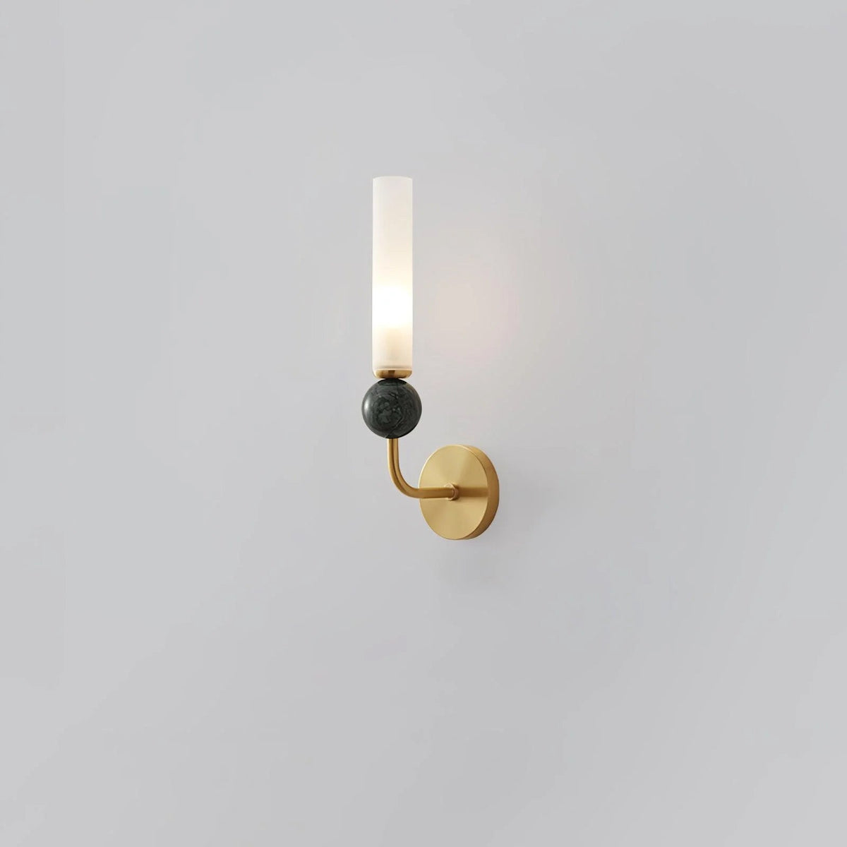 Angled against a plain grey background, a Clérachic brass-arm wall sconce shows off its green marble orb up close.