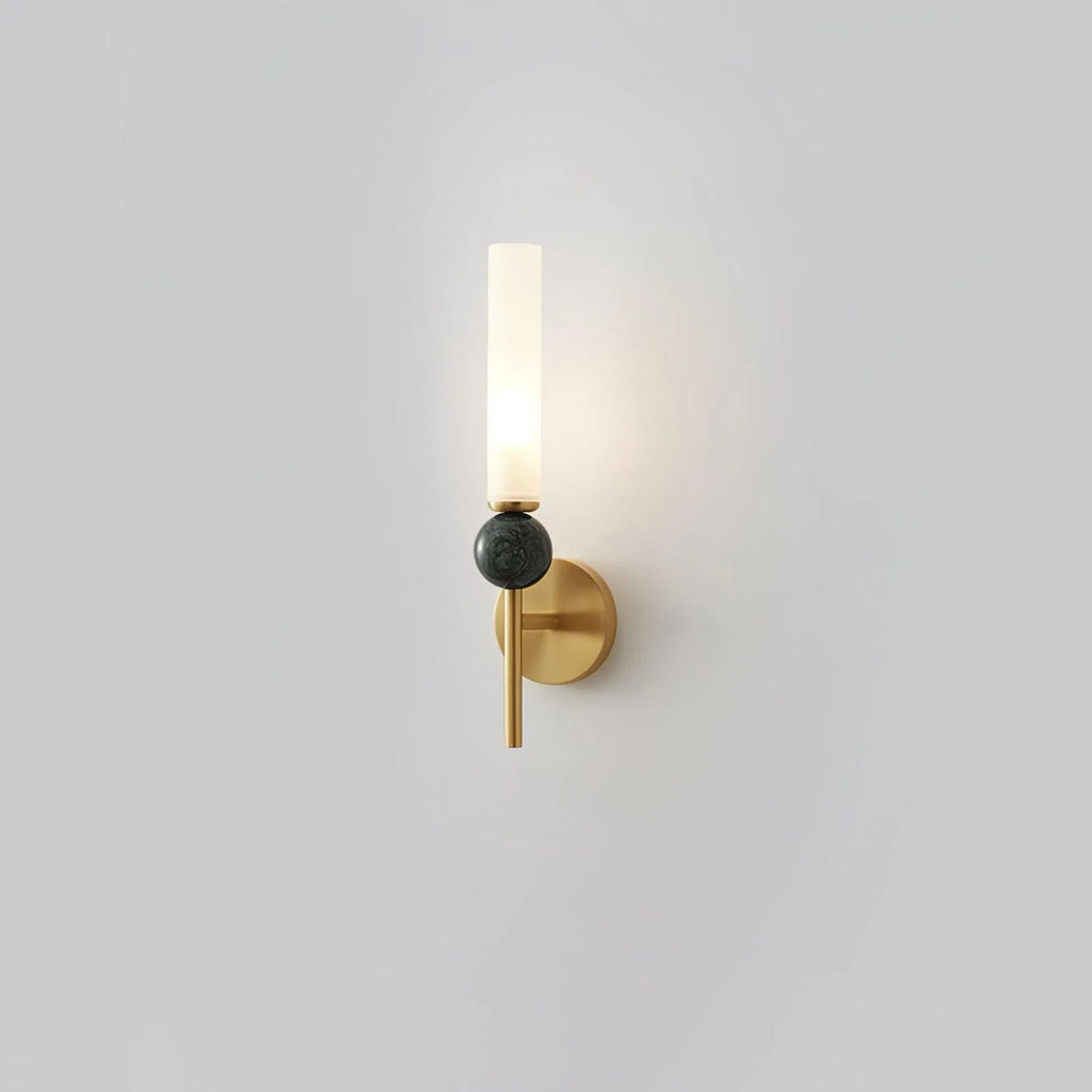 Set alone against grey, this Clérachic brass-arm wall sconce holds a green marble orb, lit at the top.