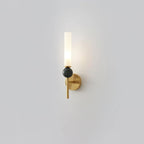 Set alone against grey, this Clérachic brass-arm wall sconce holds a green marble orb, lit at the top.