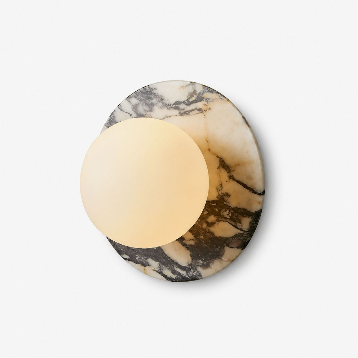 A marble disc wall sconce from Clérachic on a plain white background, its frosted opal globe lit warm against pale grey veining.