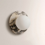 A second close-up of the grey-veined marble Clérachic wall sconce, showing the opal globe seated flush against the disc's edge.