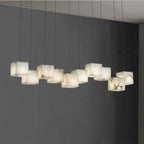 Ten-head Ivnoros chandelier lit against a grey wall, warm light escaping the base of each cube.