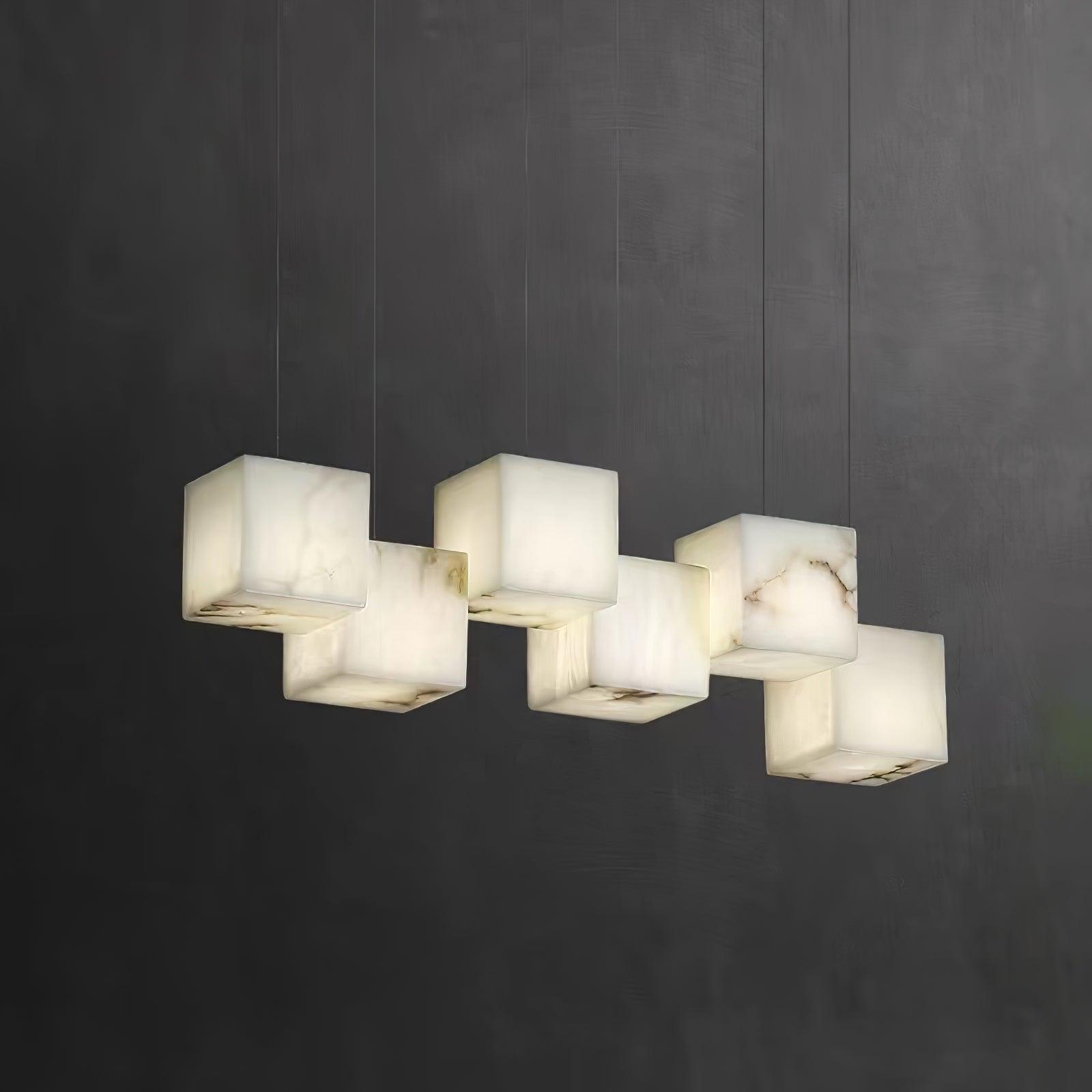 Six-head Ivnoros chandelier lit against a dark charcoal wall, each alabaster cube glowing warm.