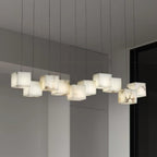 Ten-head Ivnoros chandelier lit in a pale grey room, seen from below along the line of the bar.