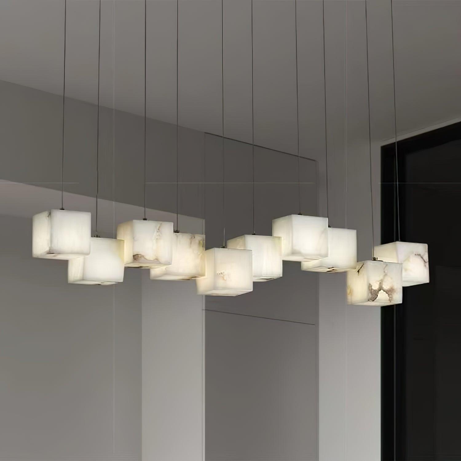 Ten-head Ivnoros chandelier lit in a pale grey room, seen from below along the line of the bar.