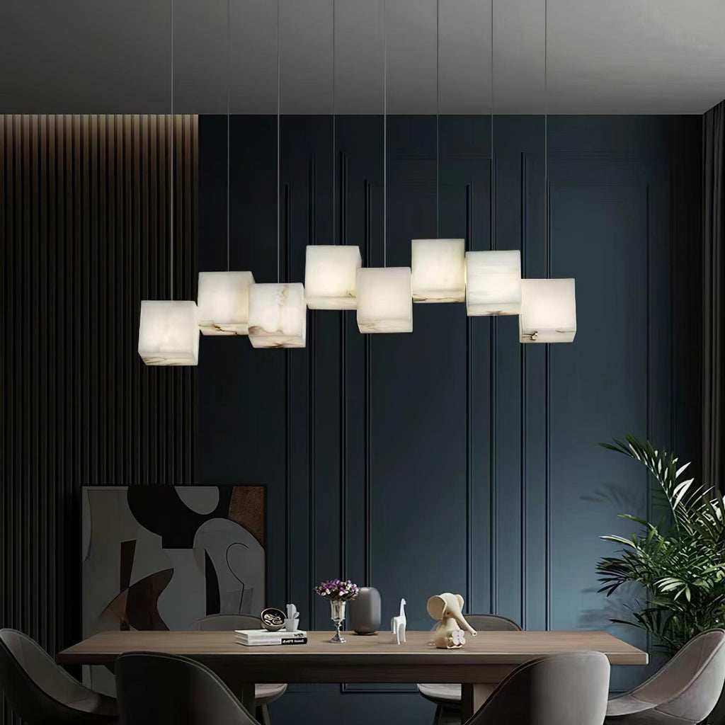 Ivnoros alabaster chandelier glowing above a walnut dining table against a deep navy panelled wall.