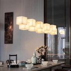 Lit Ivnoros chandelier above a dining table set with a tea service, reflected in the window beyond.
