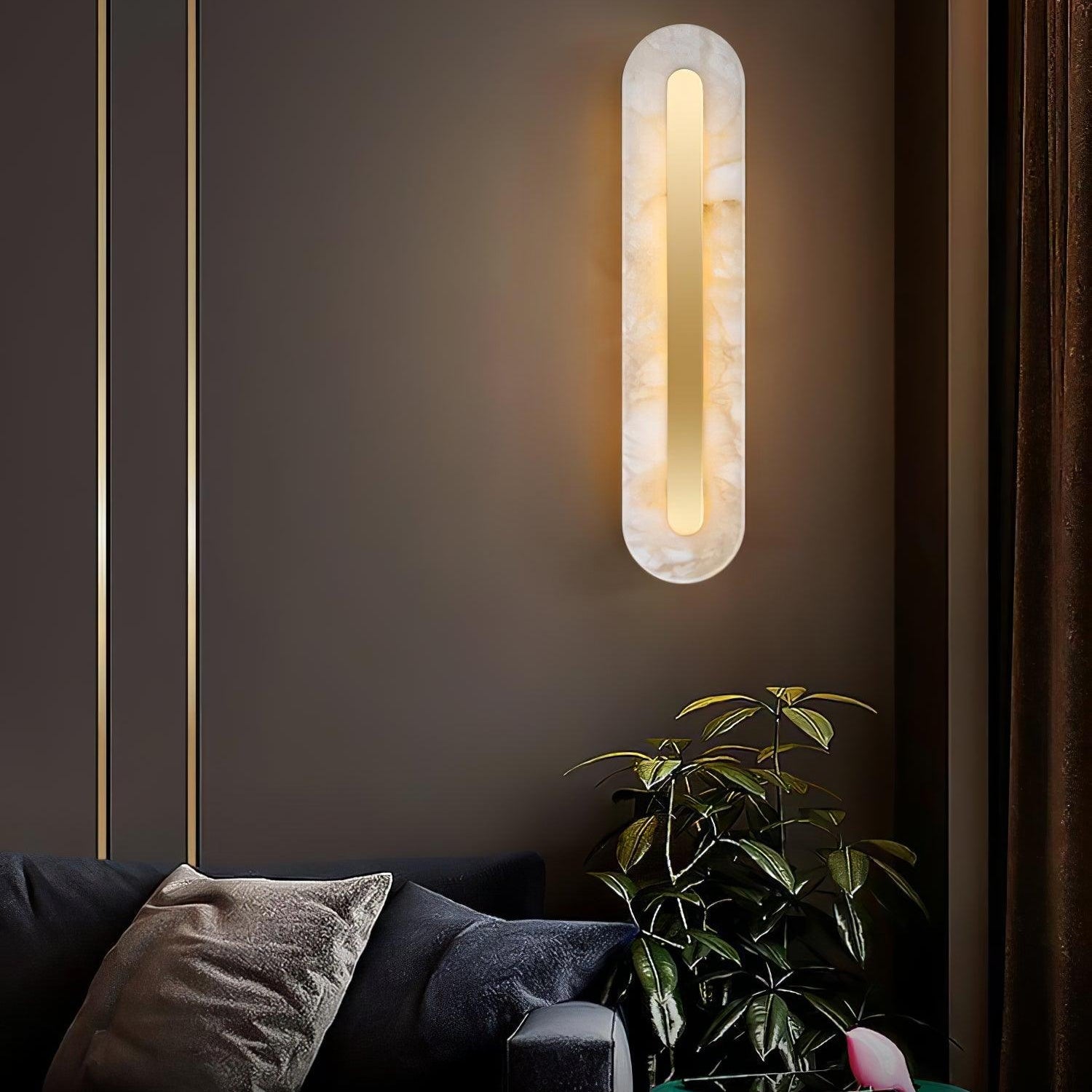 Clérachic selvia wall light casting a warm halo on a taupe wall above a dark sofa and leafy plant